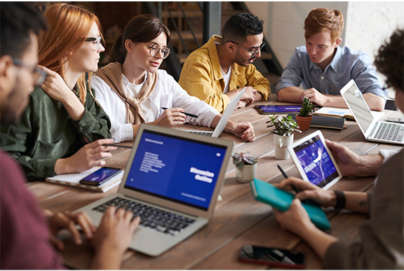 Young business people around a table with laptops