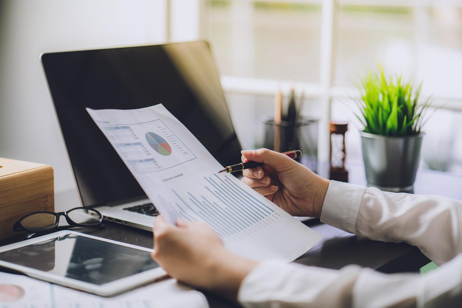 The accountant checking documents about graph and chart relating to financial reporting and tax accounting of the company